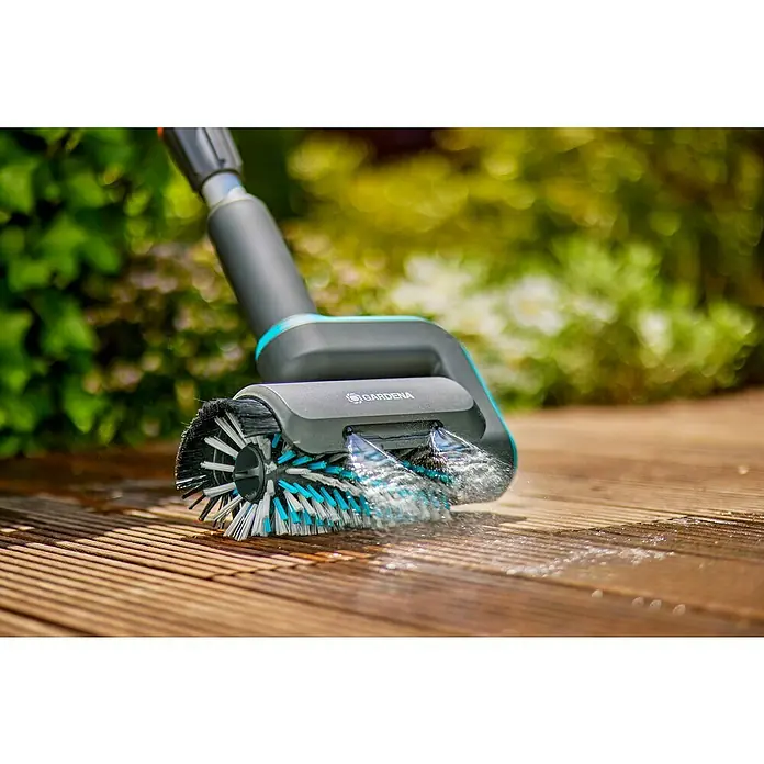 Gardena Power for All 18V Akku-Reinigungsbürste AquaBrush Patio 03/18V - 1 Akku - Nahaufnahme einer Gardena Bürste, die eine Holzterrasse mit Wasser reinigt, für eine effiziente und mühelose Reinigung im Garten.