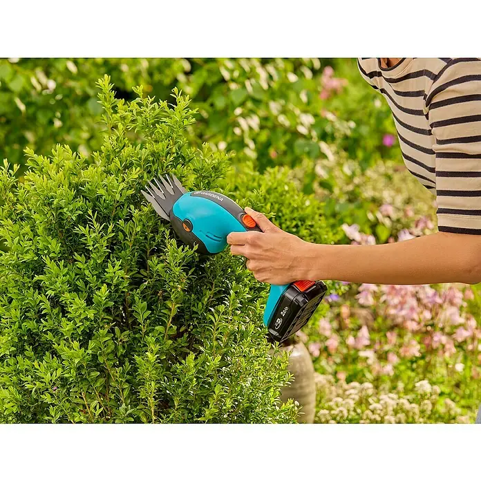 Gardena Power for All 18V Akku-Gras- & Strauchschere 20/18V P4A - 18 V, Li-Ionen, Ohne Akku - Nahaufnahme einer Frau, die mit einer Gardena-Strauchschere einen Buchsbaum beschneidet.