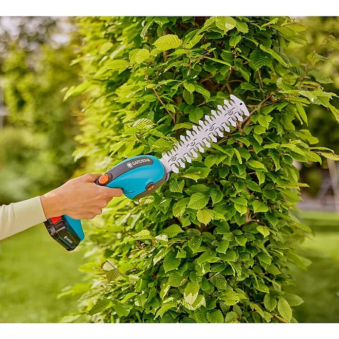 Gardena Power for All 18V Akku-Gras- & Strauchschere 20/18V P4A - 18 V, Li-Ionen, Ohne Akku - Eine Gardena Akku-Strauchschere im Einsatz, die eine grüne Hecke schneidet. Ideal für präzise Gartenarbeit.