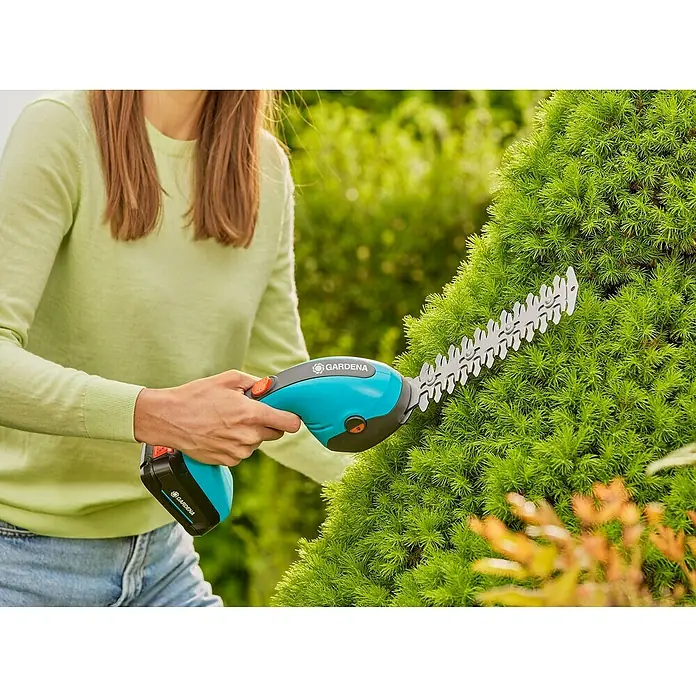 Gardena Power for All 18V Akku-Gras- & Strauchschere 20/18V P4A - 18 V, Li-Ionen, Ohne Akku - Nahaufnahme einer Frau, die eine Gardena Akku-Grasschere zum Beschneiden eines grünen Busches im Garten verwendet.