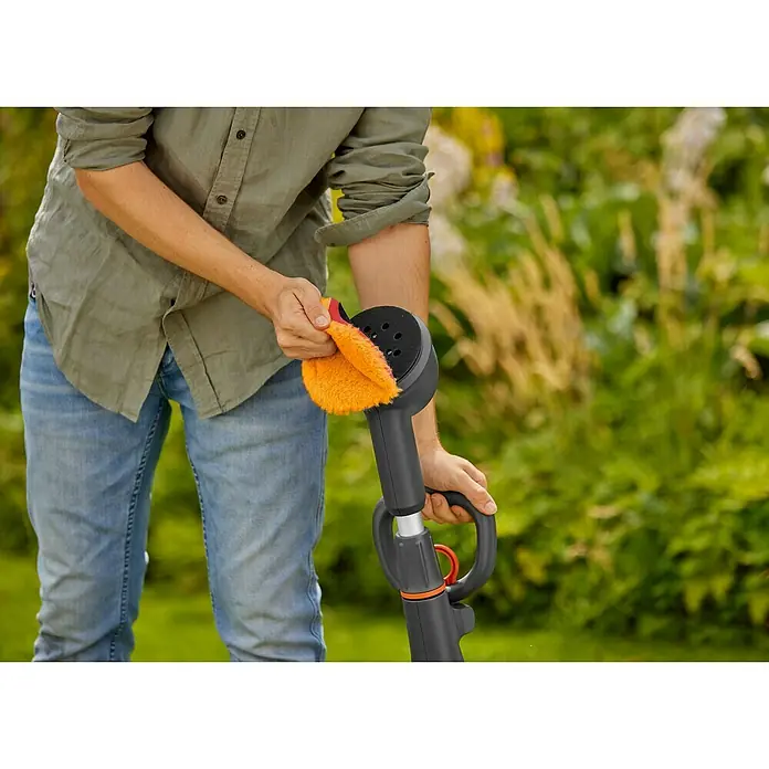 Gardena Power for All 18V Akku-Reinigungsbürste AquaBrush Compact 02/18V - Ohne Akku - Eine Person reinigt eine GARDENA Akku-Fugenbürste EasyWeed 18V P4A mit einem orangenen Tuch. Die Bürste ist schwarz mit orangenen Akzenten.