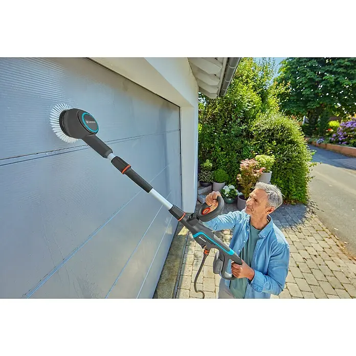 Gardena Power for All 18V Akku-Reinigungsbürste AquaBrush Compact 02/18V - Ohne Akku - Der Mann reinigt das Garagentor mit der rotierenden Bürste von Gardena, einem praktischen Werkzeug für die Außenreinigung.