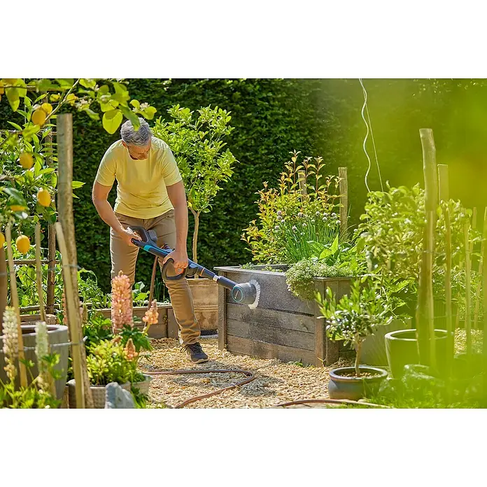 Gardena Power for All 18V Akku-Reinigungsbürste AquaBrush Compact 02/18V - Ohne Akku - Mann reinigt eine hölzerne Pflanzkiste im Garten mit einer GARDENA Bürste, um sie sauber und frisch für die Bepflanzung vorzubereiten.
