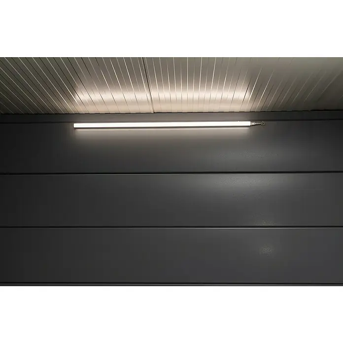 Telluria Gerätehaus Classico 3030 mit Lounge L links inkl. Elektro-Set - Außenmaß inkl. Dachüberstand (B x T): 662 x 318 cm, Stahl, Anthrazit, Inkl. Innenwandverkleidung & Elektro-Set - Eine lange, schmale, weiße Leuchtstoffröhre ist an einer grauen Wand unter einer Decke mit Streifen angebracht und spendet helles, gleichmäßiges Licht.