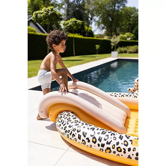 Swim Essentials Piscina hinchable - 203 x 173 x 89 cm, Leopardo - Niño jugando en un tobogán inflable de piscina con estampado de leopardo al borde de la piscina.