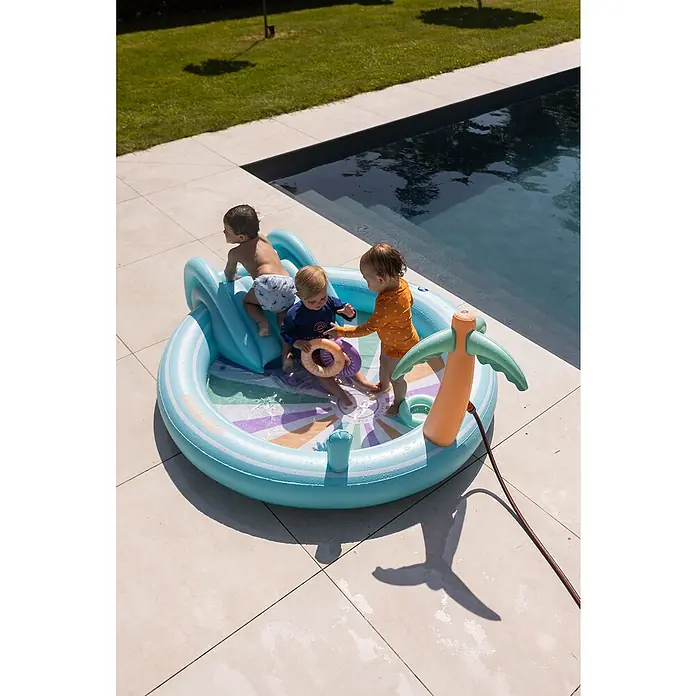 Swim Essentials Planschbecken - 203 x 173 x 89 cm, Regenbogen - Ein erfrischender Tag: Drei Kinder planschen vergnügt in einem bunten Planschbecken mit Rutsche und Palme im Garten am Pool.