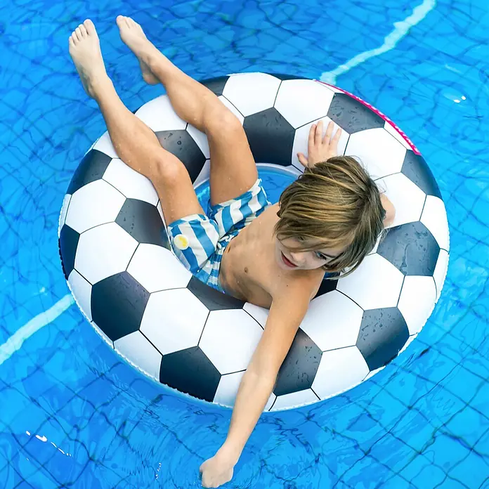 Swim Essentials Schwimmring - Durchmesser: 90 cm, Fussball - Junge im Fußball-Schwimmreifen, der sich an einem heißen Tag im erfrischenden Pool entspannt. Der Reifen sorgt für Spaß und Sicherheit im Wasser.