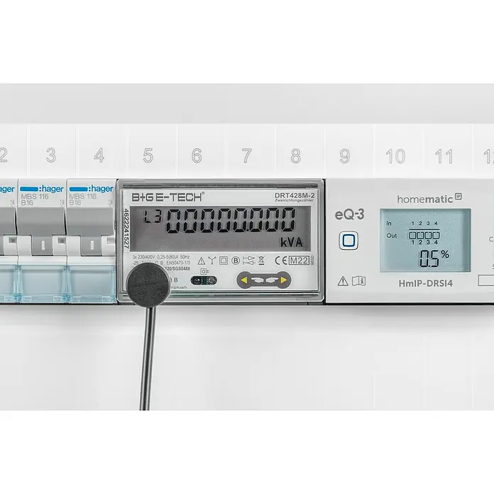 Homematic IP Kontakt-Schnittstelle HmIP-ESI-LED für digitale Stromzähler - Batteriebetrieben - Nahaufnahme eines B+G E-Tech DRT428M-2 Stromzählers, der "L3 00000000" und "kVA" anzeigt, neben einem Homematic-Gerät.