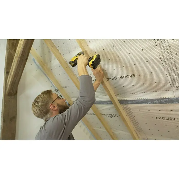 Steico Dampfbremsfolie multi renova - 50 x 1,5 m, 75 m² - Ein Mann befestigt eine Steico multi renova Dampfbremsbahn mit einem gelben Akkuschrauber an einer Holzkonstruktion.