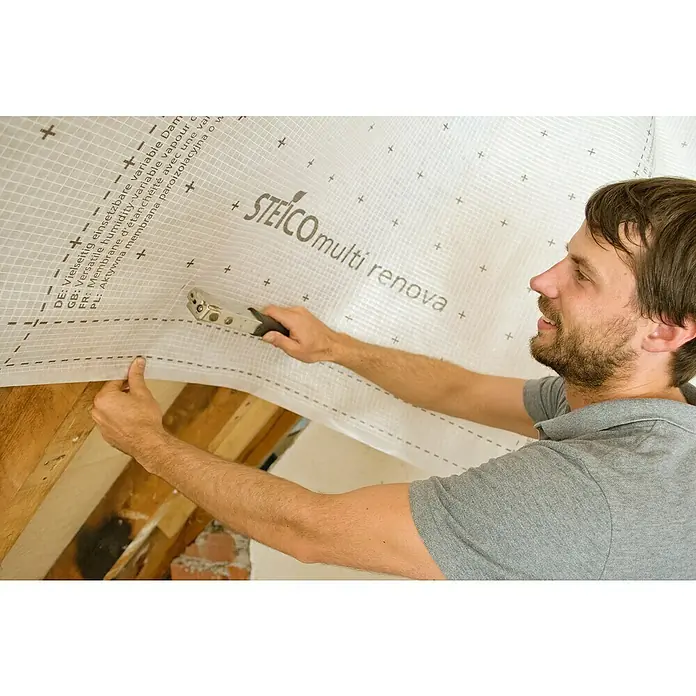 Steico Dampfbremsfolie multi renova - 50 x 1,5 m, 75 m² - Ein Mann befestigt eine STEICO multi renova Dampfbremsfolie mit einem Tacker an einer Dachkonstruktion.