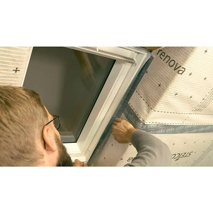 Steico Klebeband multi tape F - 25 m x 60 mm - Ein Mann montiert Steico Renovaplatten um ein Dachfenster, um die Isolierung zu verbessern. Das Produkt ist für die Innendämmung konzipiert.