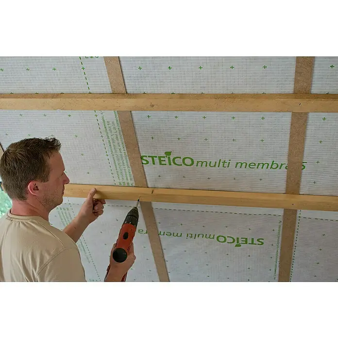 Steico Dampfbremsfolie multi membra 5 - 50 x 1,5 m, 75 m² - Ein Mann befestigt eine STEICO multi membra Dampfbremsbahn an einer Holzkonstruktion mit einem Akkuschrauber.