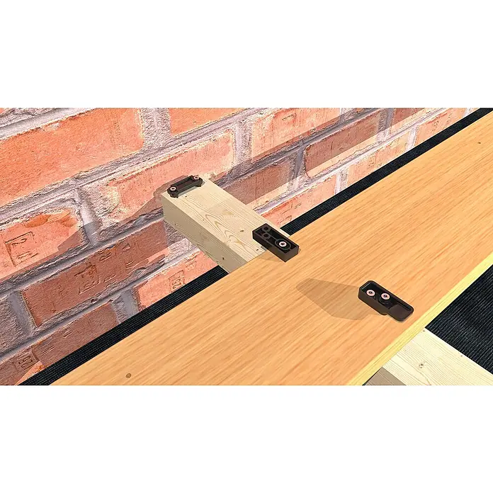 HS Terra Fixierung Plankfix Clip - 10 Stk., Passend für: HS Terra Plankfix Stick - Detailansicht einer Holzkonstruktion mit schwarzen Verbindungsstücken an einer Ziegelwand, die Stabilität und Befestigung demonstriert.
