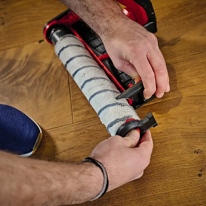 Einhell Bürstenwalze Cleanexxo - Passend für: Einhell Akku-Hartbodenreiniger Cleanexxo - Eine Nahaufnahme eines Mannes, der eine Bürstenrolle an einem Staubsauger befestigt, wobei der Fokus auf der Bürstenrolle liegt.