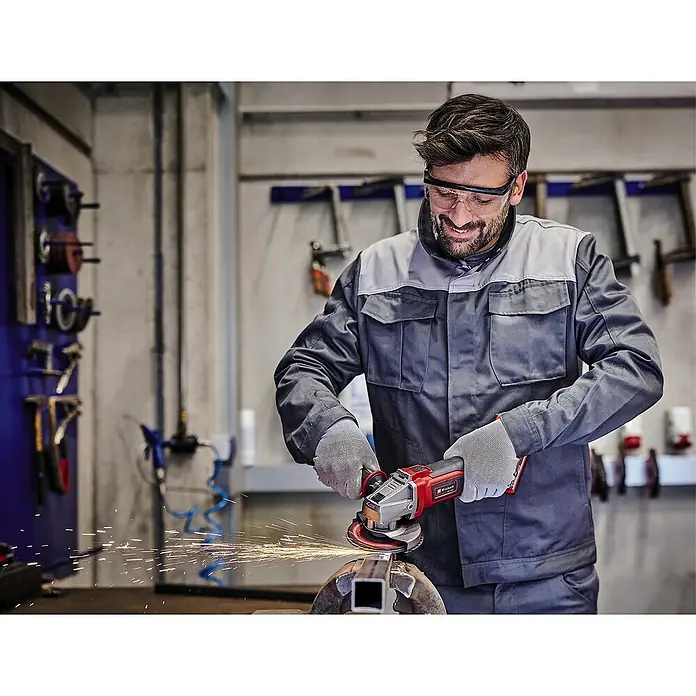 Einhell Power X-Change 18V Akku-Winkelschleifer - 18 V, Ohne Akku, Durchmesser Scheibe: 115 mm - Mann mit Schutzbrille bearbeitet Metall mit einem Einhell Winkelschleifer, Funken fliegen.