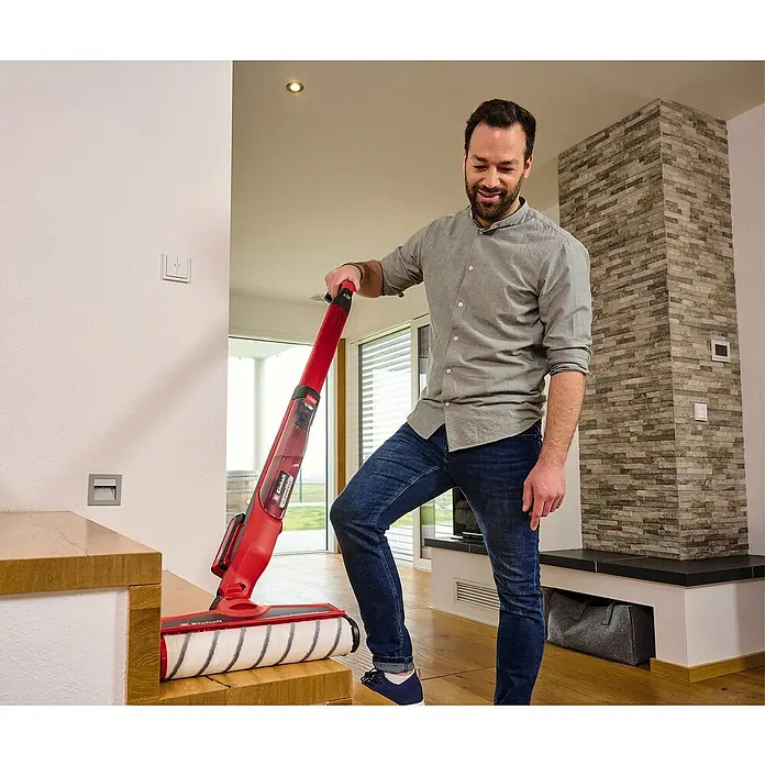 Einhell Power X-Change 18V Akku-Hartbodenreiniger Cleanexxo - 18 V, Ohne Akku - Ein Mann benutzt einen roten Einhell Akku-Nass-Trockensauger, um eine Treppe zu reinigen. Der Sauger ist kabellos und vielseitig einsetzbar.