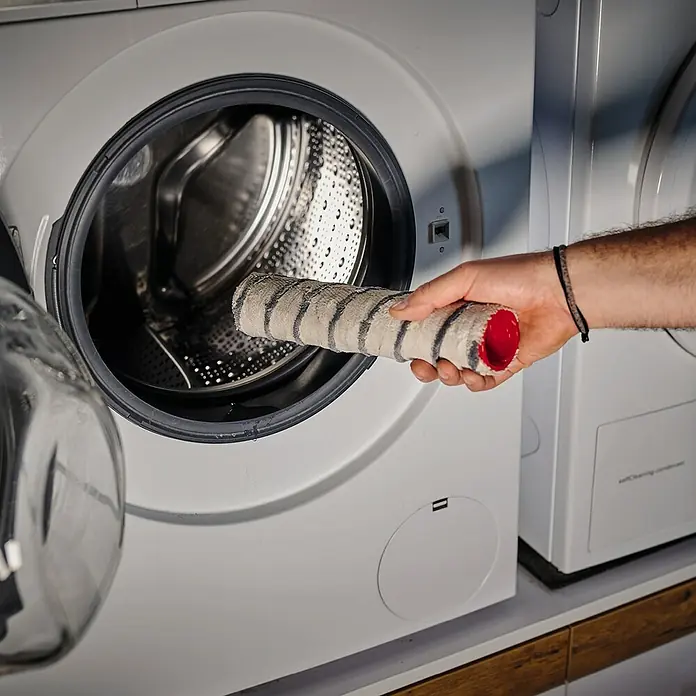 Einhell Bürstenwalze Cleanexxo - Passend für: Einhell Akku-Hartbodenreiniger Cleanexxo - Ein Mann legt eine mit Farbe verschmutzte Farbwalze in eine Waschmaschine, um sie zu reinigen.