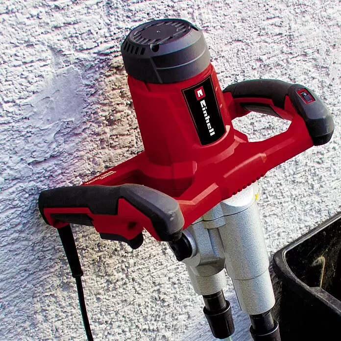 Einhell Farb- & Mörtelmischer TE-MX 1600-2 CE TWIN - Durchmesser Rührer: 120 mm, Sechskant - Rotes und schwarzes Einhell Mörtelrührwerk an strukturierter Wand, bereit zum Mischen von Baustoffen.