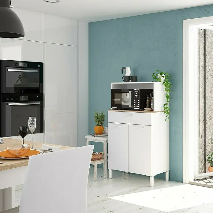 Aparador buffet Kira - L x An x Al: 40 x 72 x 126 cm, Blanco Artik/Roble Canadian, Número de cajones: 1 ud., Número de puertas: 2 ud. - Vista de la cocina con un mueble de cocina blanco con microondas, platos y plantas. El mueble ofrece almacenamiento y espacio de trabajo.