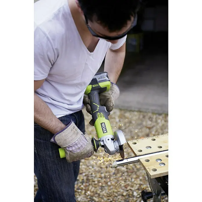 Ryobi ONE+ Akku-Winkelschleifer R18AG-0 - Li-Ionen, Ohne Akku, Durchmesser Scheibe: 115 mm, 7.500 U/min - Ein Mann benutzt einen Ryobi Akku-Winkelschleifer, um Metall zu schneiden, während Funken fliegen. Er trägt dabei Schutzbrille und Handschuhe.