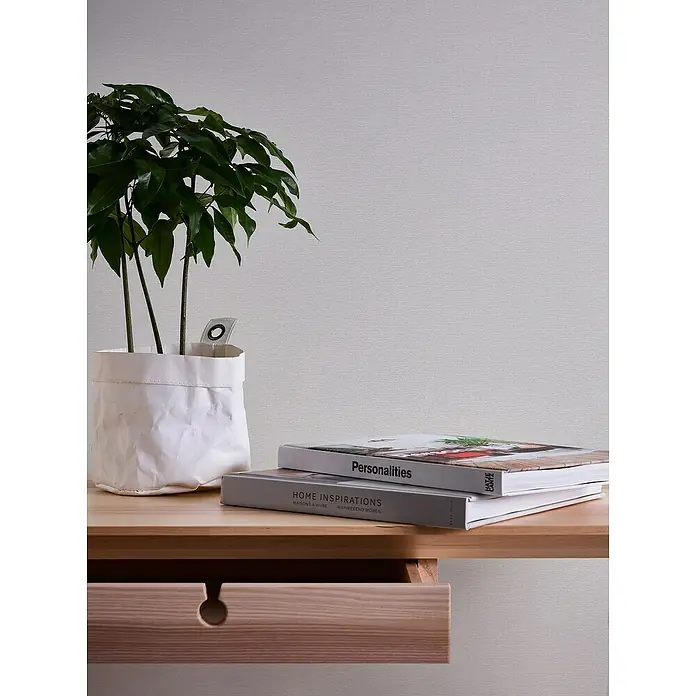 A.S. Création Casual Living Vliestapete Textilstruktur - Grau, Uni, 10,05 x 0,53 m - Dekorative Holzkommode mit Pflanze und Büchern. Das perfekte Möbelstück, um jedem Raum einen Hauch von Stil und Wärme zu verleihen.