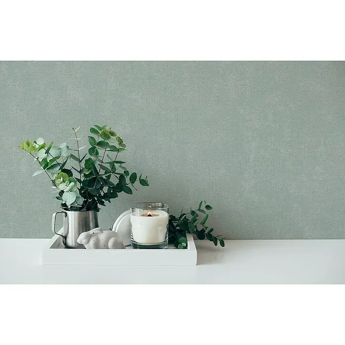 A.S. Création Casual Living Vliestapete - Mintblau, Uni, 10,05 x 0,53 m - Kerze in Glas, Dekofigur Hase, Eukalyptus in Metallbecher auf weißem Tablett vor hellgrünem Hintergrund.