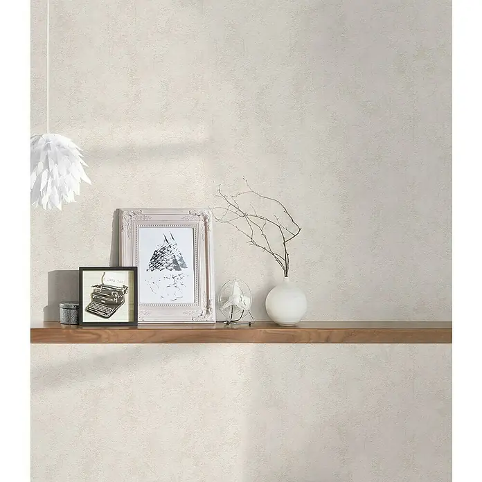 A.S. Création Casual Living Vliestapete - Creme, Uni, 10,05 x 0,53 m - Detailaufnahme eines Wandregals mit Vintage-Dekorationen wie Bilderrahmen, einer Schreibmaschine und einer Vase mit Zweigen.