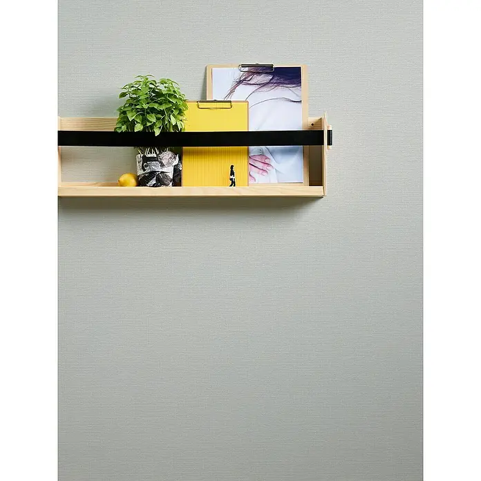 A.S. Création Casual Living Vliestapete - Strukturgrau, Uni, 10,05 x 0,53 m - Ein hölzernes Wandregal mit einer Pflanze, gelben Ordnern und einem Foto an einer grauen Wand. Dekorative und funktionale Wandaufbewahrung.