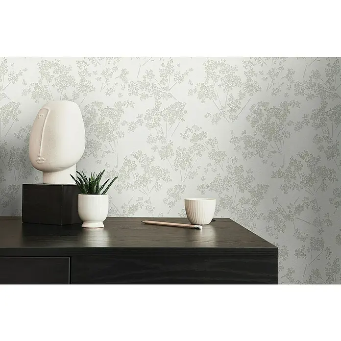 A.S. Création Casual Living Vliestapete Blümchen - Weiß/Grün/Grau, Floral, 10,05 x 0,53 m - Nahaufnahme eines Tisches mit Dekorationen vor einer strukturierten Tapete.