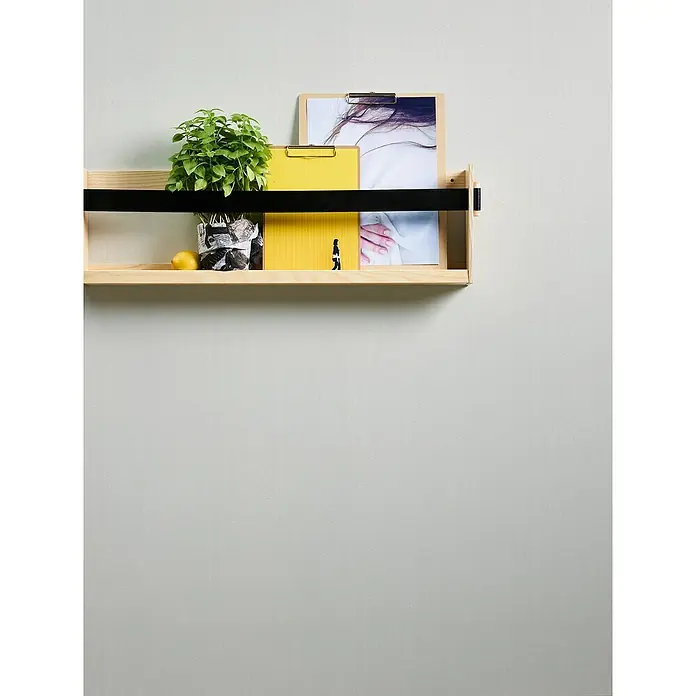 A.S. Création Casual Living Vliestapete - Weiß, Uni, 10,05 x 0,53 m - Ein helles Holzregal mit einer schwarzen Stange beherbergt eine Pflanze, gelbe Blöcke und gerahmte Bilder an einer hellgrauen Wand.