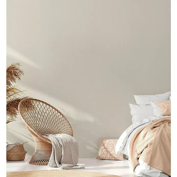 A.S. Création Casual Living Vliestapete - Creme/Weiß, Uni, 10,05 x 0,53 m - Einladendes Schlafzimmer mit einem Korbstuhl, weichen Textilien und natürlichen Elementen, die eine entspannende und ruhige Atmosphäre schaffen.