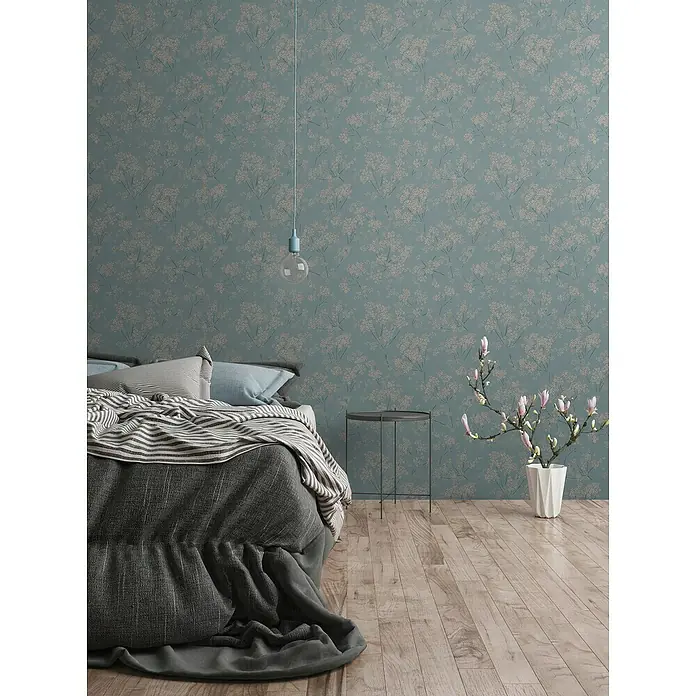 A.S. Création Casual Living Vliestapete Blümchen - Blau/Beige/Türkis, Floral, 10,05 x 0,53 m - Schlafzimmer mit floraler Tapete in Blautönen, einem Bett mit grauer Decke und Holzboden.
