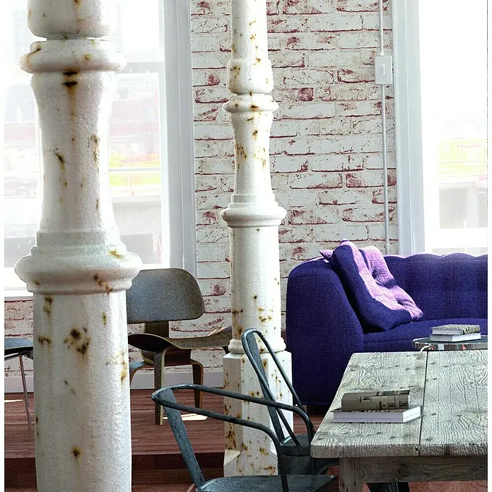 A.S. Création Casual Living Vliestapete New England Klinker - Weiß/Rot, Steinoptik, 10,05 x 0,53 m - Dieses Bild zeigt einen Wohnbereich mit einem lila Sofa, einem Holztisch und zwei dekorativen Säulen, die dem Raum Charakter verleihen.