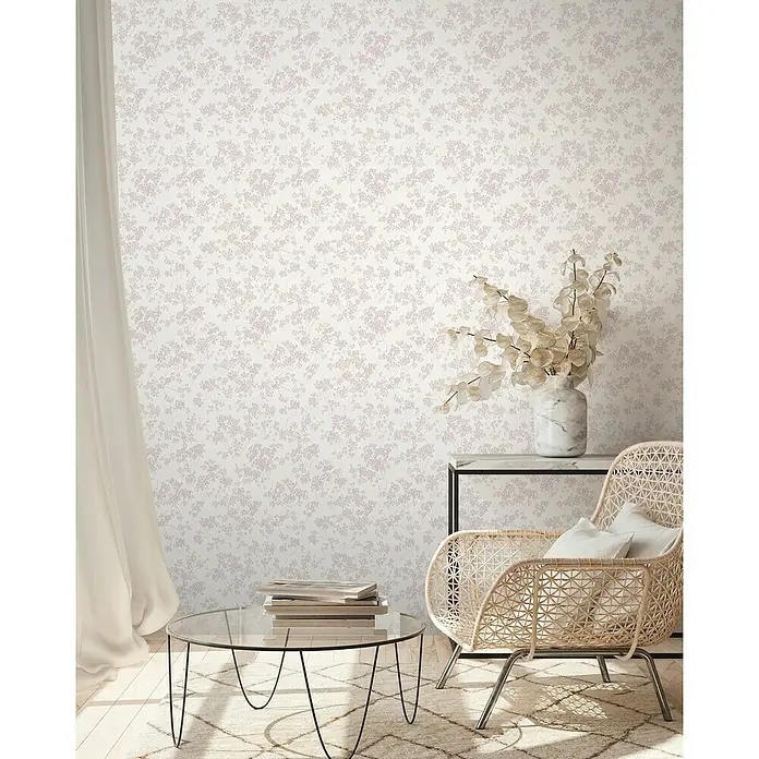A.S. Création Casual Living Vliestapete Blümchen - Weiß/Rosa, Floral, 10,05 x 0,53 m - Das Bild zeigt eine Nahaufnahme einer floralen Tapete in einem gemütlichen Wohnzimmer mit Stuhl und Tisch.