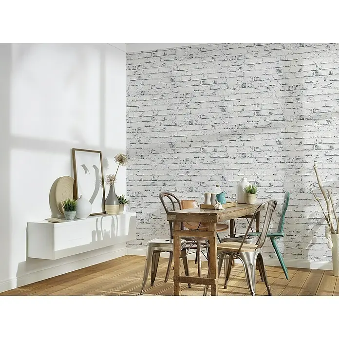 A.S. Création Casual Living Vliestapete New England Klinker - Grau/Anthrazit, Steinoptik, 10 x 0,53 m - Ein Esszimmer mit einem Holztisch und verschiedenen Stühlen, dekoriert mit Vasen, Pflanzen und einem Wandregal.