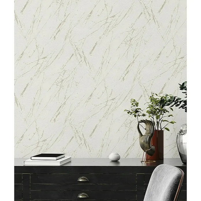 A.S. Création Casual Living Vliestapete Marmor - Weiß/Champagner/Metallic, Steinoptik, 10,05 x 0,53 m - Ein stilvolles Interieur mit einer Kommode, einer Pflanze und einer dekorativen Tapete.