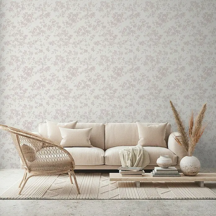 A.S. Création Casual Living Vliestapete Blümchen - Weiß/Rosa, Floral, 10,05 x 0,53 m - Wohnzimmer mit beigem Sofa, Rattan-Stuhl und floraler Tapete für ein gemütliches Ambiente.