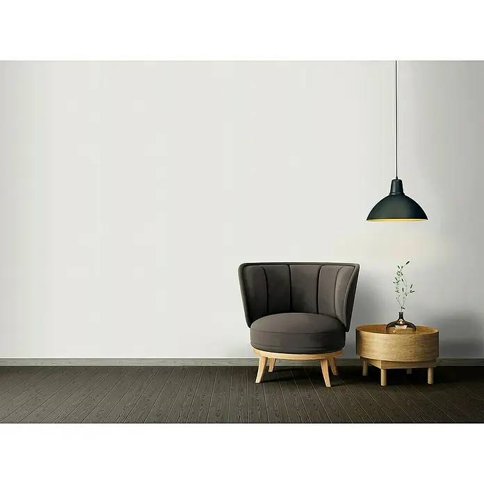 A.S. Création Casual Living Vliestapete - Creme-Weiß, Uni, 10,05 x 0,53 m - Eine graue Polstersessel mit einem Holztisch und einer Hängelampe vor einer weißen Wand. Die stilvolle Inneneinrichtung wirkt einladend.