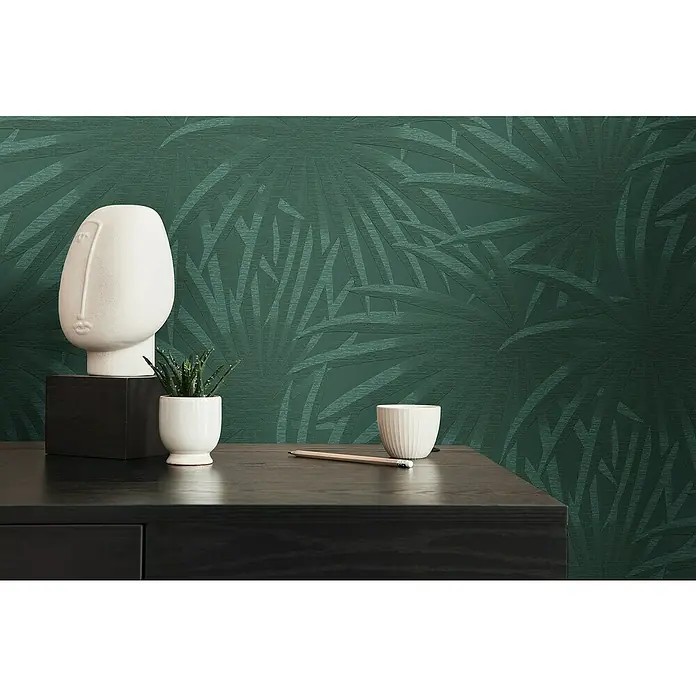 A.S. Création Casual Living Vliestapete Palmenblätter - Grün/Dunkelgrün, Floral, 10,05 x 0,53 m - Detailaufnahme eines Interieurs mit einer weißen Skulptur und einer grünen Akzentwand mit Palmenmuster.