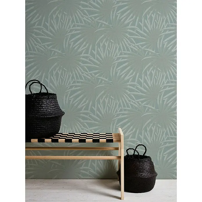 A.S. Création Casual Living Vliestapete Palmenblätter - Blau/Mint, Floral, 10,05 x 0,53 m - Zwei schwarze Körbe und eine helle Holzbank mit Schachbrettmuster vor einer grün-weißen floralen Tapete. Vielseitige Aufbewahrungslösung.