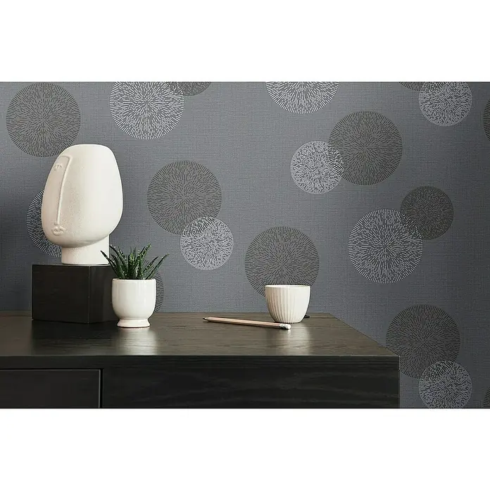 A.S. Création Casual Living Vliestapete Kreise - Anthrazitgrau, Grafisch, 10,05 x 0,53 m - Nahaufnahme eines modern eingerichteten Raumes mit einer stilvollen Kommode, einer Skulptur und einer Zimmerpflanze.