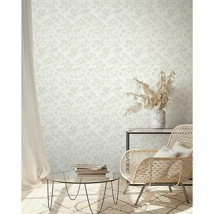 A.S. Création Casual Living Vliestapete Blümchen - Weiß/Grün/Grau, Floral, 10,05 x 0,53 m - Stilvolles Wohnzimmer mit Rattan-Sessel, Glascouchtisch und floraler Tapete, das eine moderne und gemütliche Atmosphäre schafft.