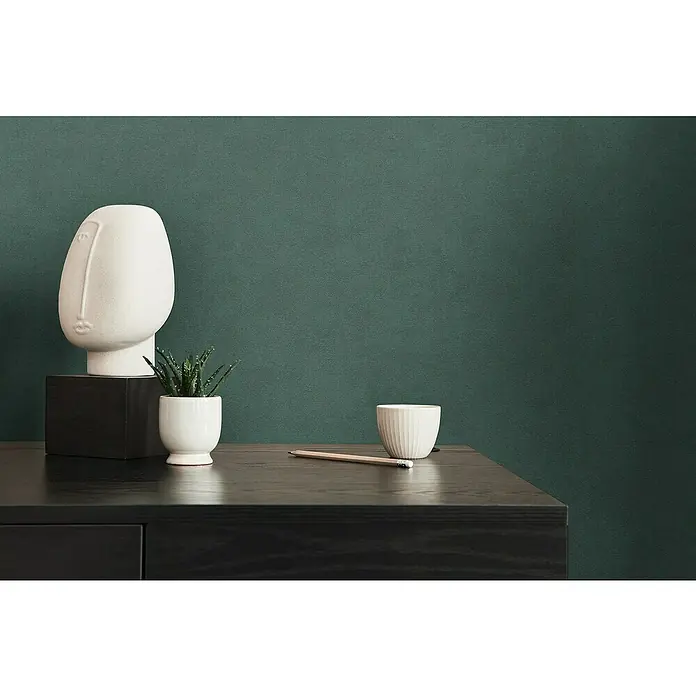 A.S. Création Casual Living Vliestapete - Grün, Uni, 10,05 x 0,53 m - Nahaufnahme einer Kommode mit Dekorationen wie einer weißen Skulptur, einem Bleistift, Topf und einer Pflanze.