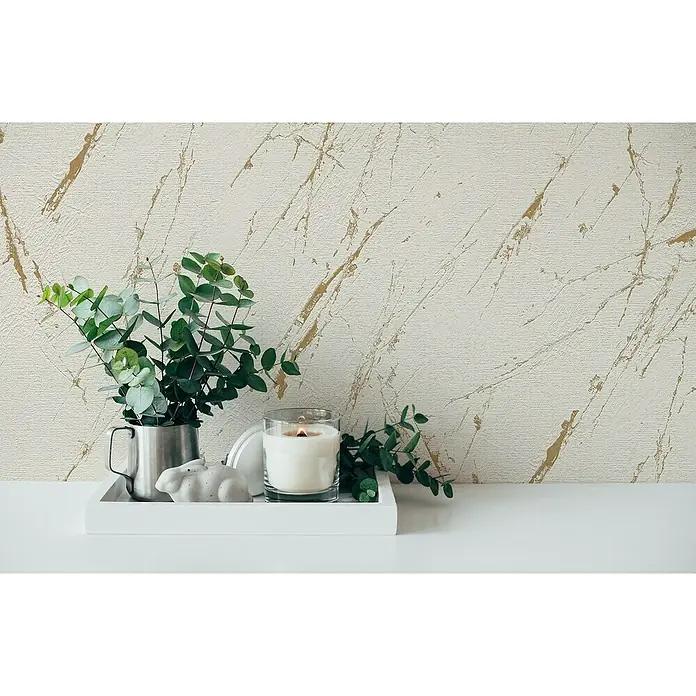 A.S. Création Casual Living Vliestapete Marmor - Beige/Gold/Metallic, Steinoptik, 10,05 x 0,53 m - Kerze und Pflanze auf einem weißen Tablett vor einer marmorierten Wand.