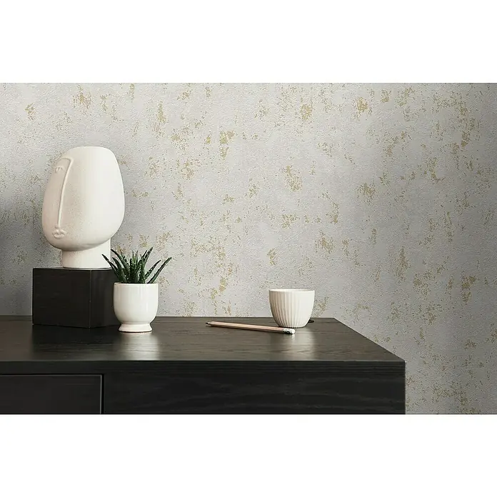 A.S. Création Casual Living Vliestapete Struktur - Grau/Gold/Metallic, Uni, 10,05 x 0,53 m - Nahaufnahme eines stilvollen Tisches mit Deko-Objekten wie einer abstrakten Skulptur, einer Pflanze und einer Schale, die ein modernes Ambiente schaffen.
