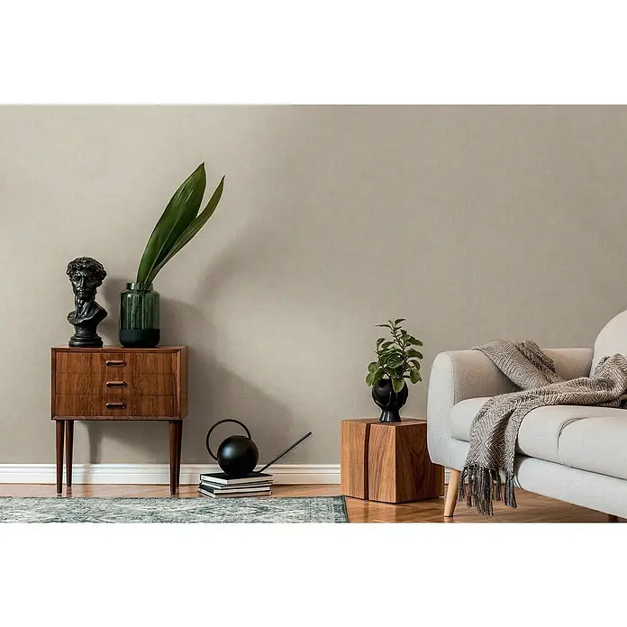 A.S. Création Casual Living Vliestapete - Grau/Beige, Uni, 10,05 x 0,53 m - Einrichtung mit einem Beistelltisch aus Holz, einer Skulptur, Pflanzen in Vasen und einem bequemen Sofa, das eine gemütliche Atmosphäre schafft.