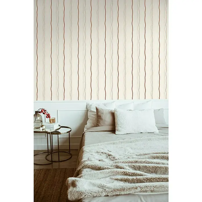 A.S. Création Casual Living Vliestapete - Creme/Rot/Beige, Streifen, 10,05 x 0,53 m - Elegante Schlafzimmeransicht mit einer stilvollen Tagesdecke, die Komfort und Wärme ausstrahlt, perfekt ergänzt durch die passende Bettwäsche.