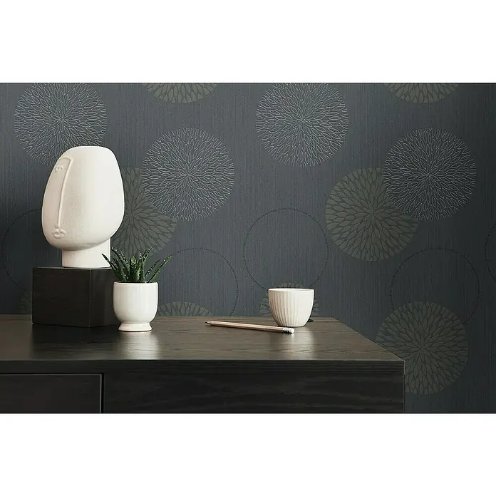 A.S. Création Casual Living Vliestapete Kreise - Anthrazit-Grau, Grafisch, 10,05 x 0,53 m - Dekorative Nahaufnahme mit abstraktem Kopf, Sukkulente, Bleistift und Schale auf dunklem Tisch vor gemusterter Wand.