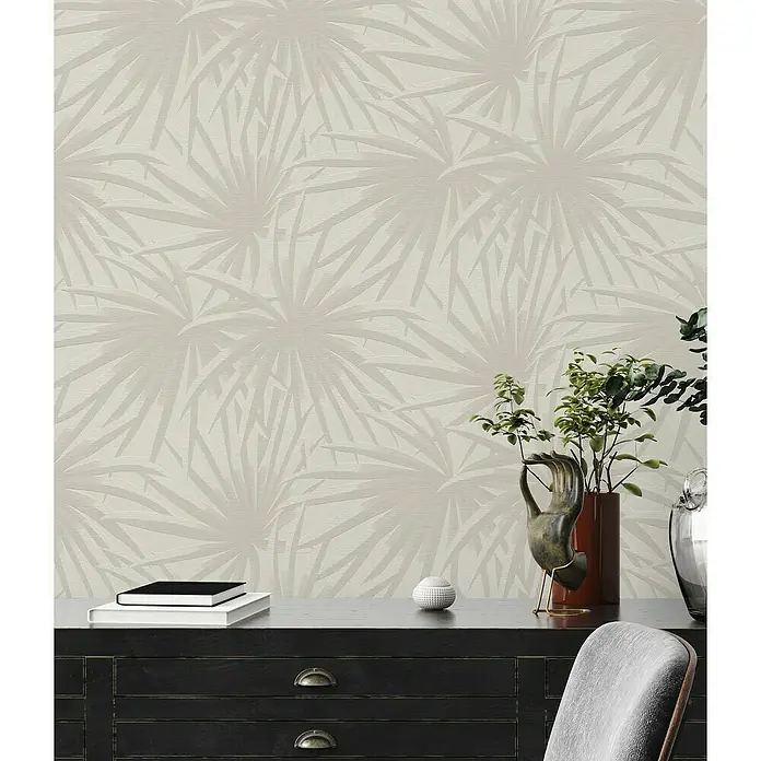 A.S. Création Casual Living Vliestapete Palmenblätter - Creme/Hellgrau, Floral, 10,05 x 0,53 m - Ein Zimmer mit einer schwarzen Kommode und einer Tapete mit Palmenblättern im Hintergrund.