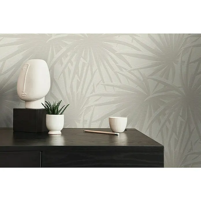 A.S. Création Casual Living Vliestapete Palmenblätter - Creme/Hellgrau, Floral, 10,05 x 0,53 m - Detailaufnahme eines stilvollen Schreibtischs mit Dekorationen und einem Bleistift vor einer Wand mit dezentem Blätterdesign.